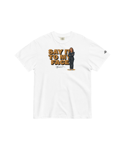 Heavyweight T-shirt in white showcasing Kamala Harris's memorable phrase "Say it to my face," paired with a stylized portrait of her and her signature beneath, creating a striking and empowering design.