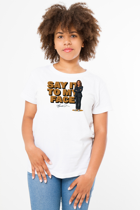 Heavyweight T-shirt in white showcasing Kamala Harris's memorable phrase "Say it to my face," paired with a stylized portrait of her and her signature beneath, creating a striking and empowering design.